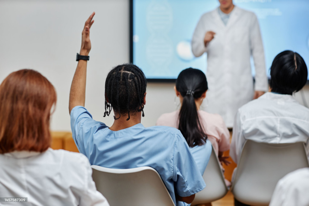 Medical lecture with student raising hand for question.